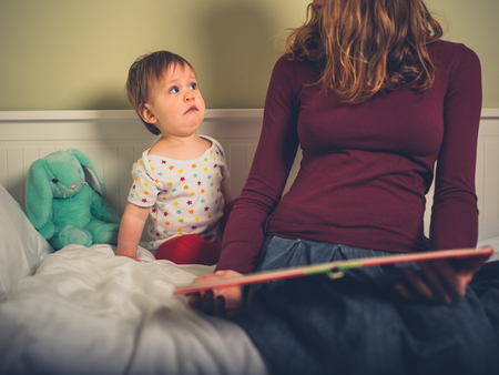 A little boy is being read to by his mother and is looking at her confusedの写真素材