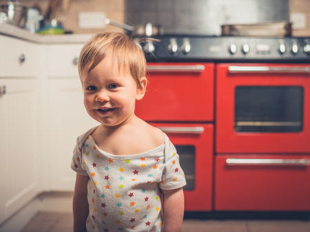 A cute little boy is standing by the stove in a kitchenの写真素材