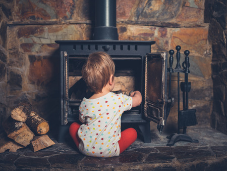 A little boy is playing with the log burnerの写真素材