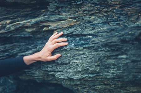 The hand of a young woman touching a rock surfaceの写真素材