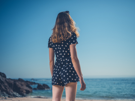 A beautiful young woman is standing on the beach in the summerの写真素材