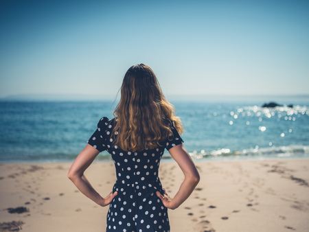 A beautiful young woman is standing on the beach in the summerの写真素材