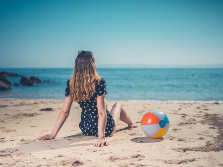 A young woman is relaxing on the beach with a beach ballの写真素材