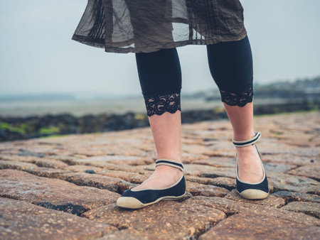 The feet of a young woman walking outside on a hard surface