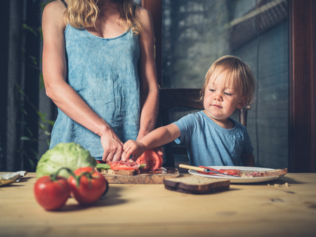 A mother and her toddler are making sandwiches at homeの写真素材