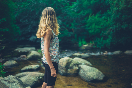 A young woman is standing by a riverの写真素材