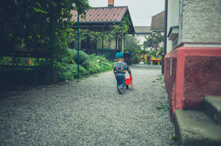 A little toddler is playing with a toy wheelbarrowの写真素材