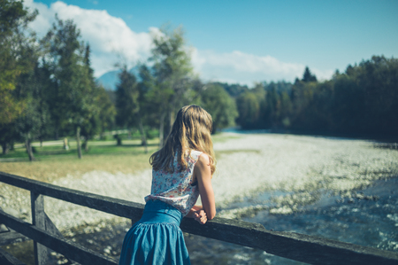 A young woman is standing on a bridge in natureの写真素材
