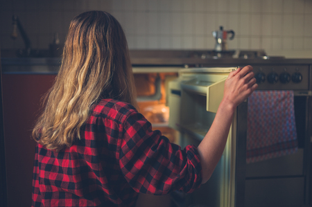 A young woman is opening the door of her fridgeの写真素材