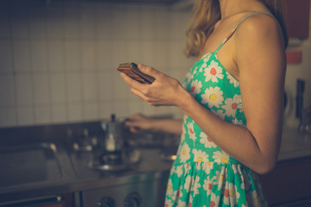 A young woman is using a smart phone at home at sunsetの写真素材