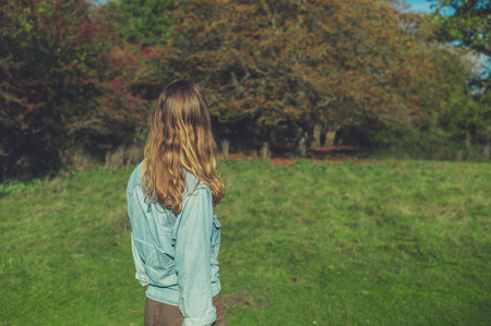 A young woman is relaxing in a meadow on a sunny autumn dayの写真素材
