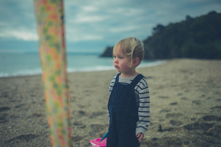 A little toddler is standing on the beach in autumnの写真素材