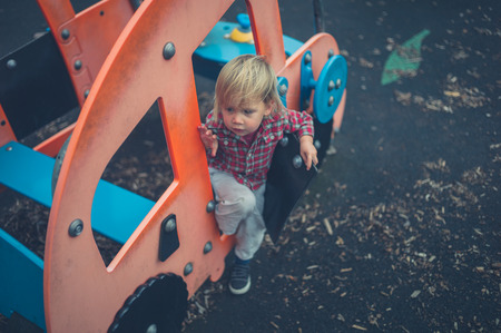 A toddler is sitting in a pretend car at the playgroundの写真素材