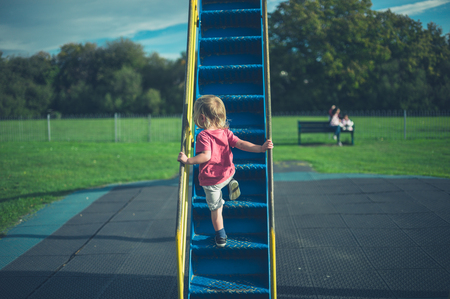 A little toddler is climbing up a slideの写真素材