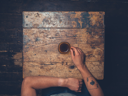 Overhead shot of man drinking coffee at a wooden tableの写真素材