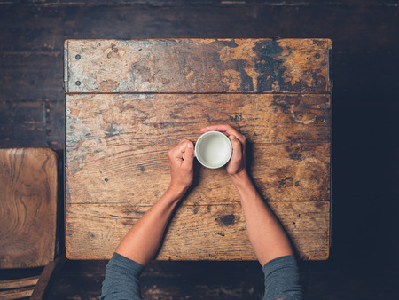 Overhead shot of a woman sitting at a table with a cupの写真素材