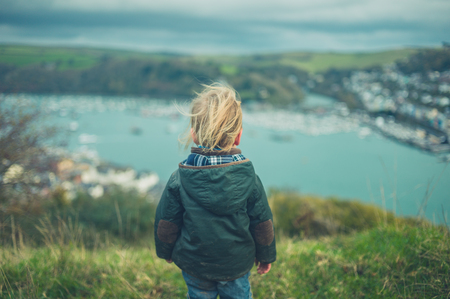 A little toddler is admiring the view of a seaside townの写真素材