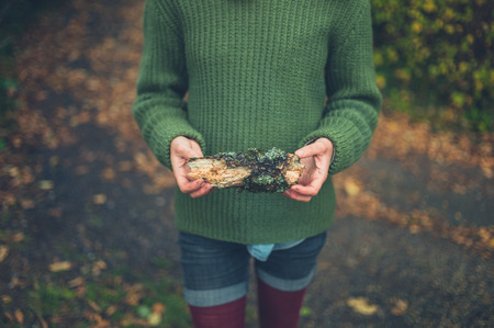 A young woman is standing in nature with a small logの写真素材