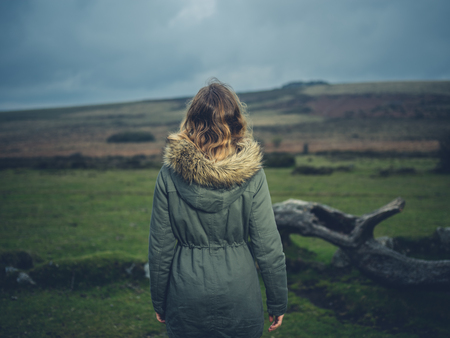 A young woman is standing by a fallen tree on the moorの写真素材