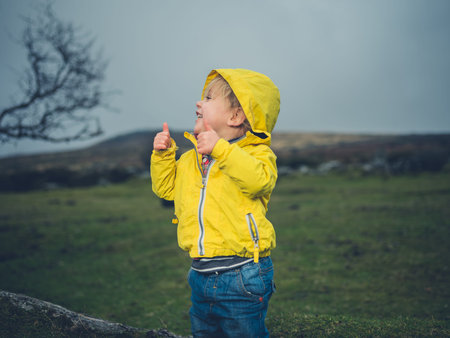 A little toddler is standing on the moor and showing thumbs up