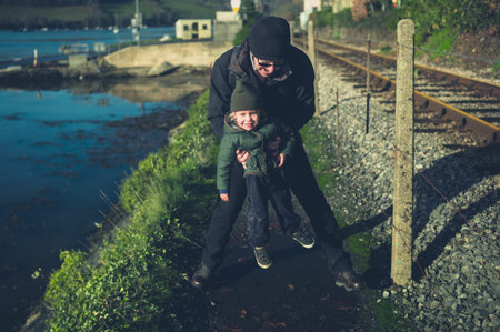 A little toddler and his grandfather are walking by the railway tracksの写真素材