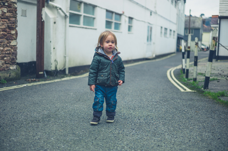 A little toddler is standing in the road by himselfの写真素材