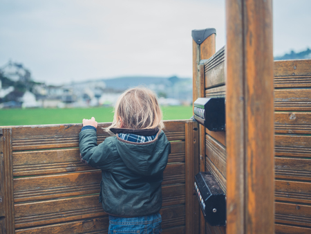 A little toddler is standing on the play equipment in a parkの写真素材