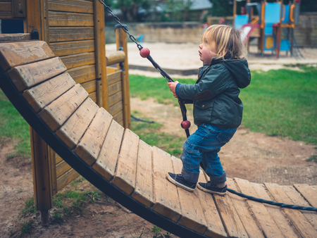 A little toddler is on the play equipment in the parkの写真素材