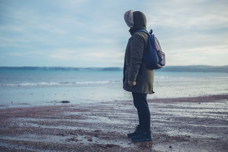 A woman is standing on the beach by the water in winterの写真素材