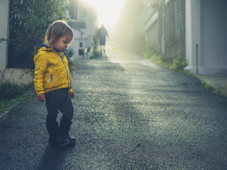 A little toddler is looking at a worm lying in the streetの写真素材