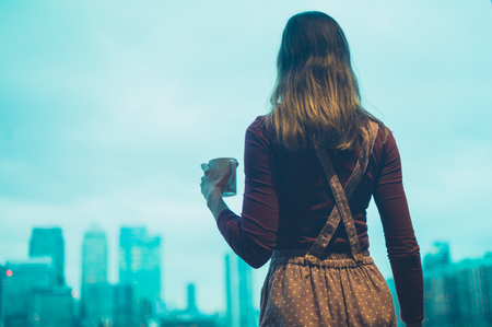 A young woman is drinking coffee in a city apartmentの写真素材