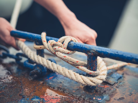 A young woman is tying up her boat with a rope on the jettyの写真素材