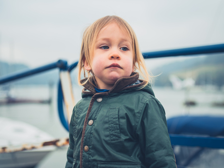 A little toddler is standing in a boatyardの写真素材