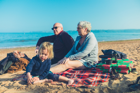 A little toddler is on the beach with his grandparentsの写真素材