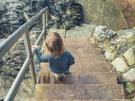 A little toddler is going down some stairs on the coastの写真素材
