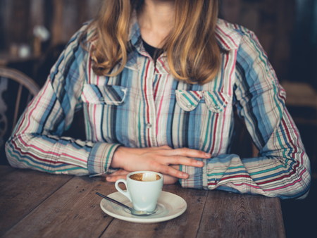 A young woman is drinking espresso in a cafeの写真素材
