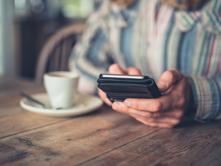 A young woman is drinking coffee and using her smartphone in a cafe