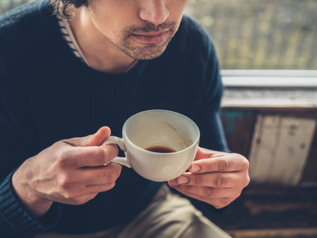 A young man is drinking coffee in a cafeの写真素材