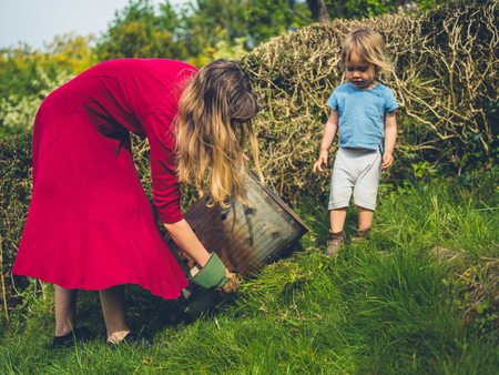 A little toddler is helping his mother weed the gardenの写真素材
