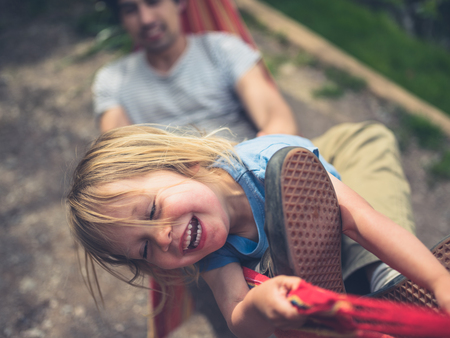 A little toddler is having fun in a hammock with his fatherの写真素材