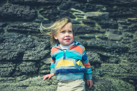 A little toddler is standing outside with the wind blowing in his hairの写真素材