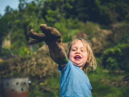 A little toddler is posing with a garden gloveの写真素材