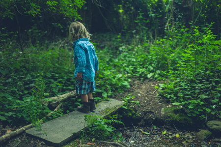 A little toddler is walking in the woods by a little brookの写真素材