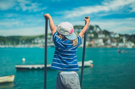 A little toddler is holding onto some railings in a small town by the riverの写真素材