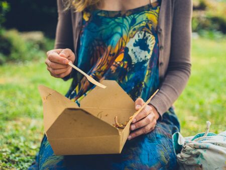 A young woman is enjoying a picnic in the parkの写真素材