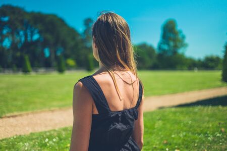 A young woman is standing in the park on a sunny summer dayの写真素材