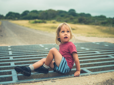 A little toddler is playing on a cattle gridの写真素材