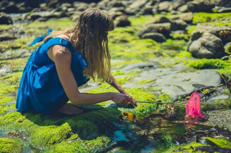 A young woman is on the beach with a fishing net in summerの写真素材