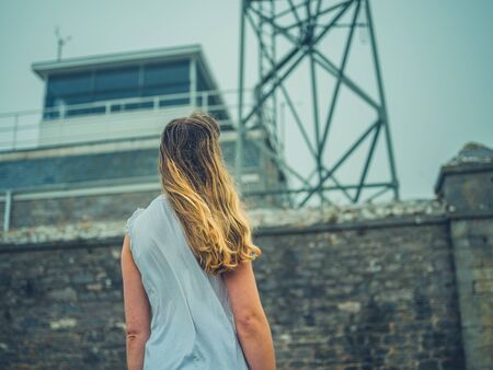 A young woman is standing outside a listening station in the fogの写真素材
