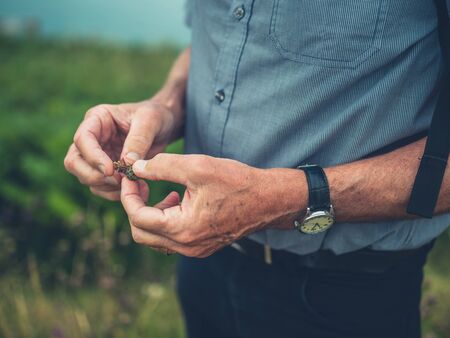 Closeup on a senior man's hands as he is holding some seeds by the coastの写真素材